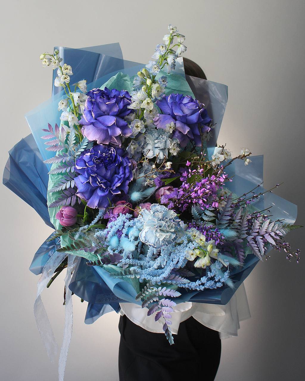 Large bouquet of purple and blue flowers wrapped in blue paper
