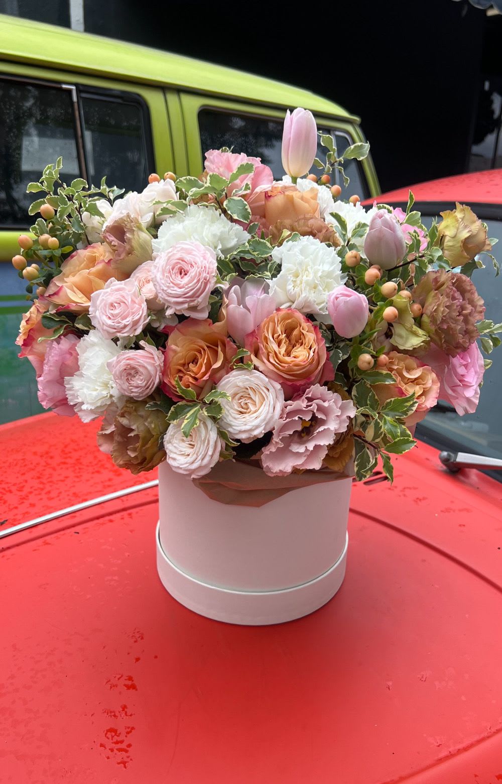 Pastel bouquet of roses, tulips, and carnations in a pink hat box