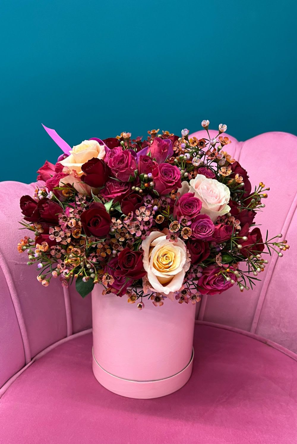 Bouquet of pink, red, and cream roses in a pink hat box