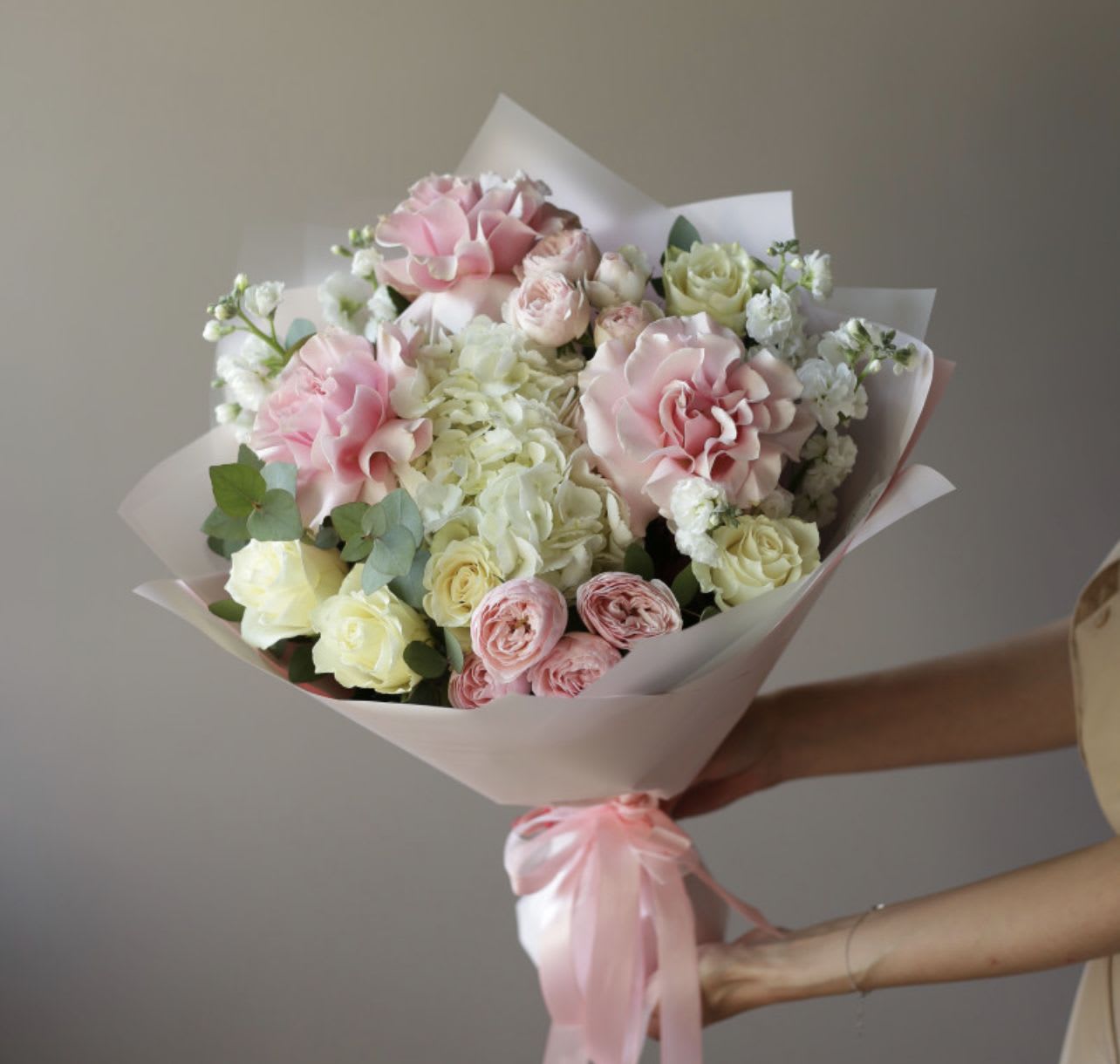 Bouquet of pink and white roses wrapped in pale paper
