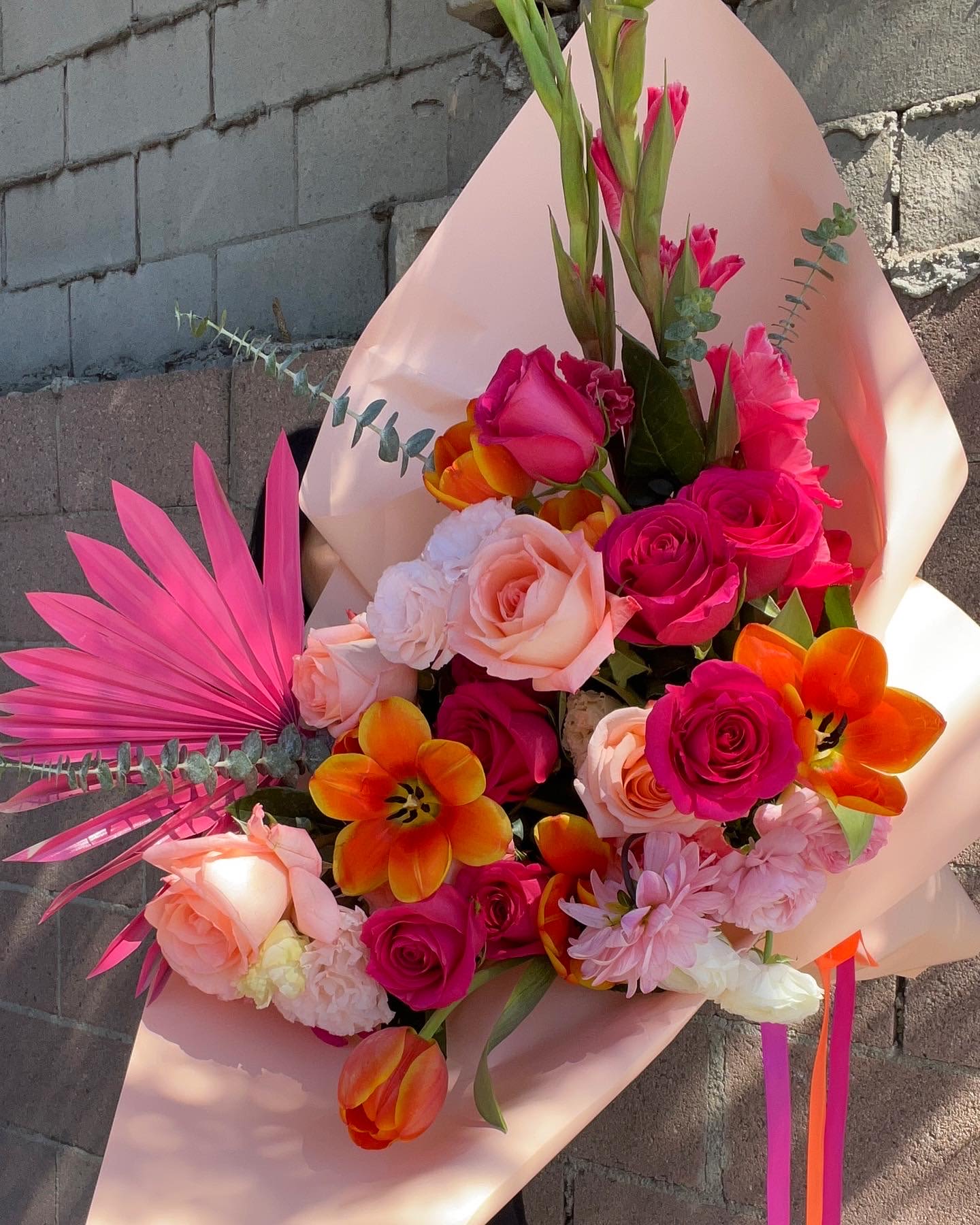 Bouquet of pink and orange roses with tulips and pink palm fronds