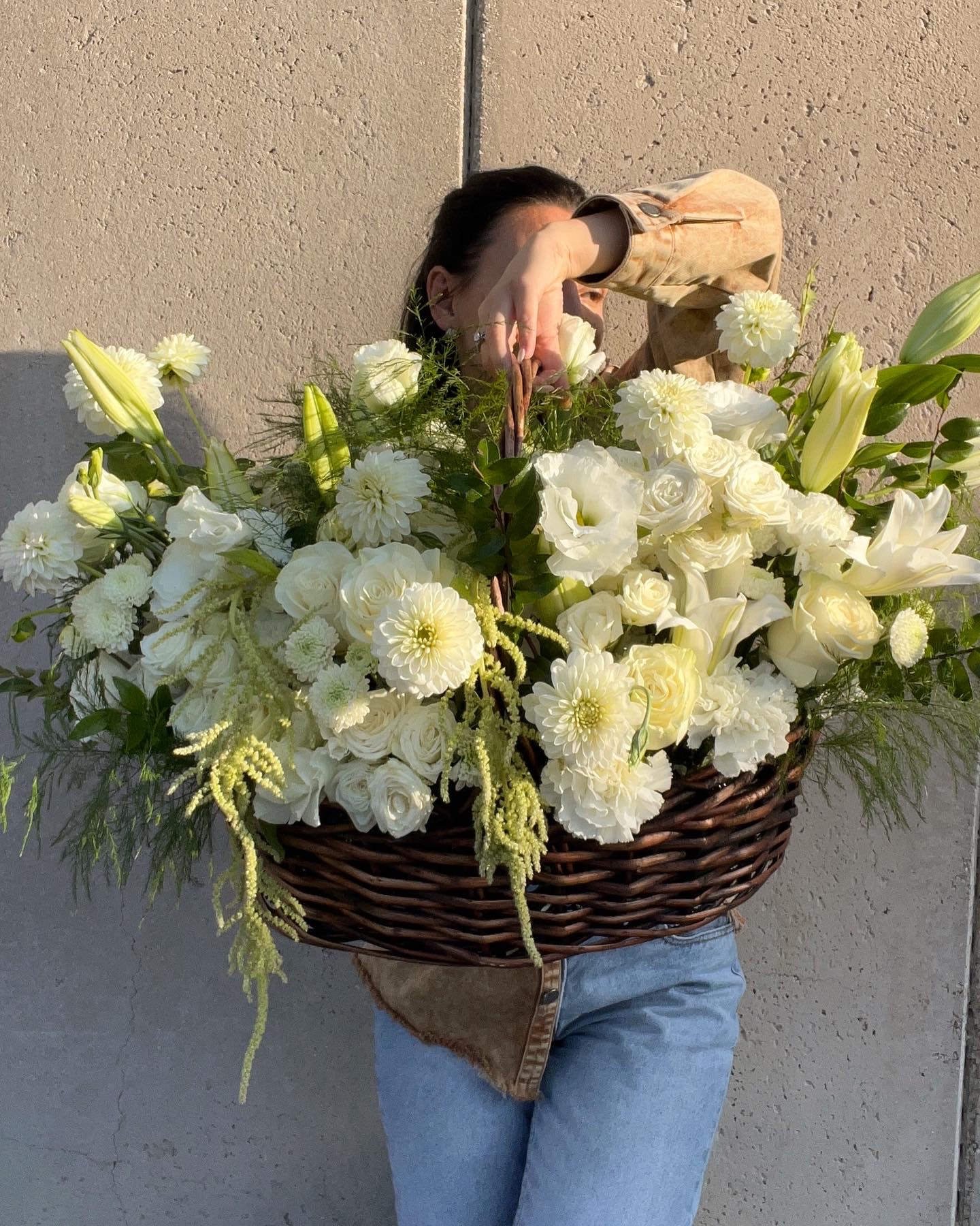 Large white flower basket with lilies, roses, and mums
