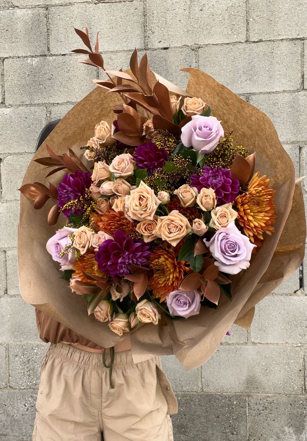 Large bouquet of roses and chrysanthemums wrapped in brown paper