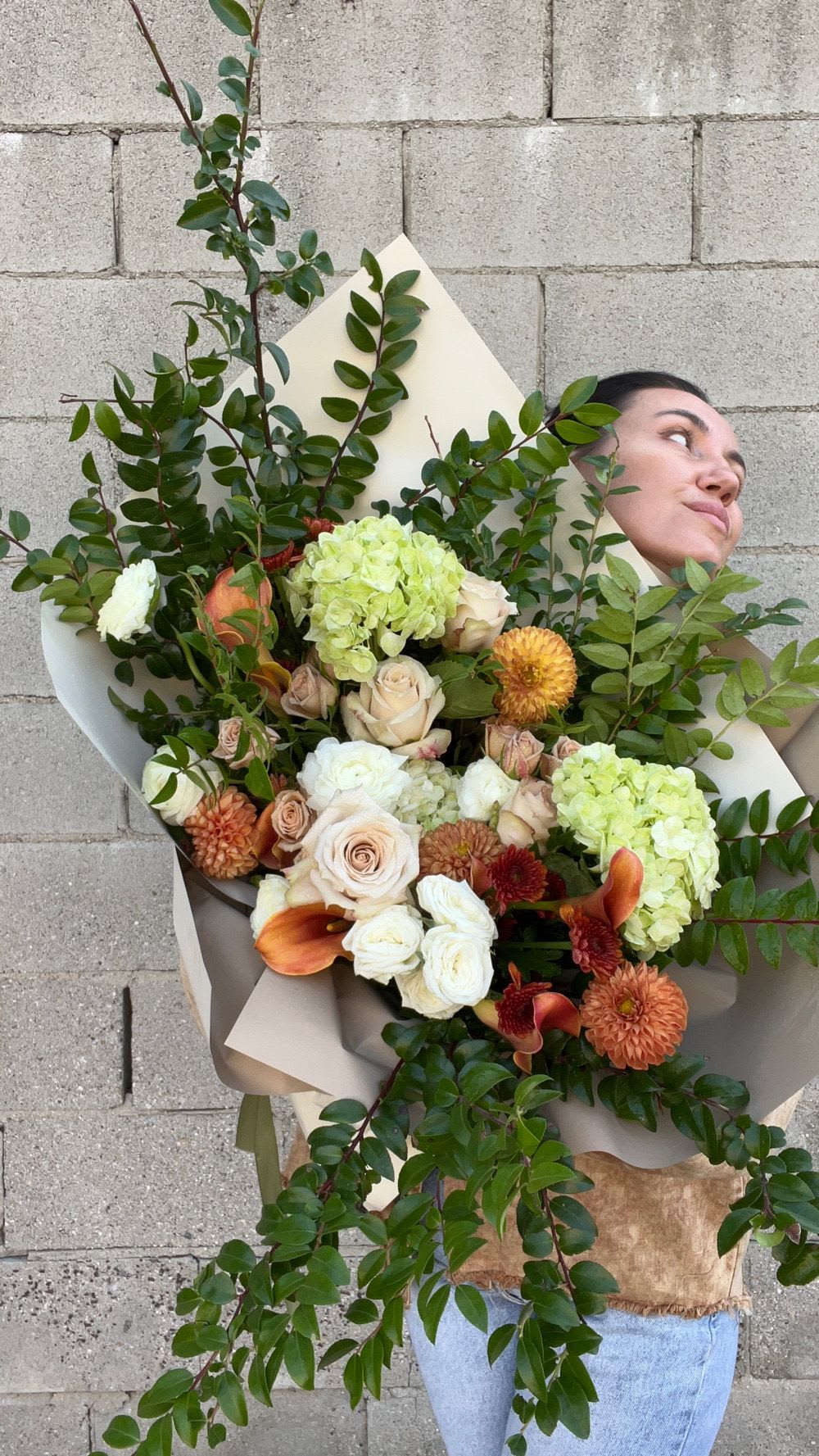 Large bouquet of pale roses, hydrangeas, and orange blooms with greenery