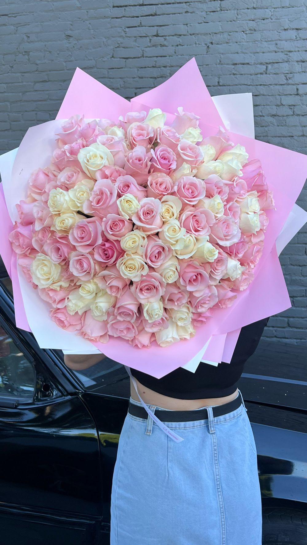 Large bouquet of pink and cream roses wrapped in pink paper