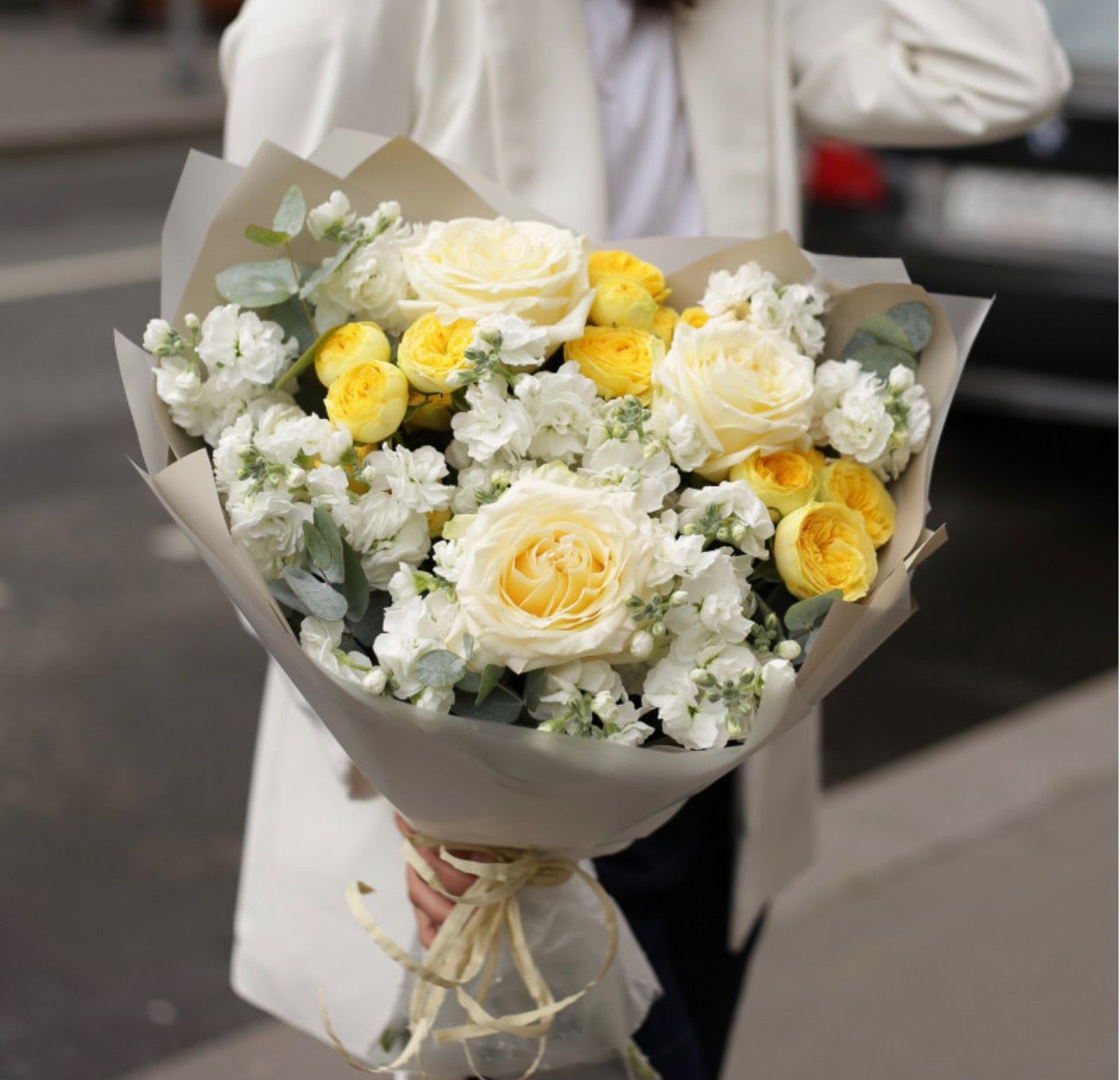 Bouquet of white and yellow roses wrapped in beige paper