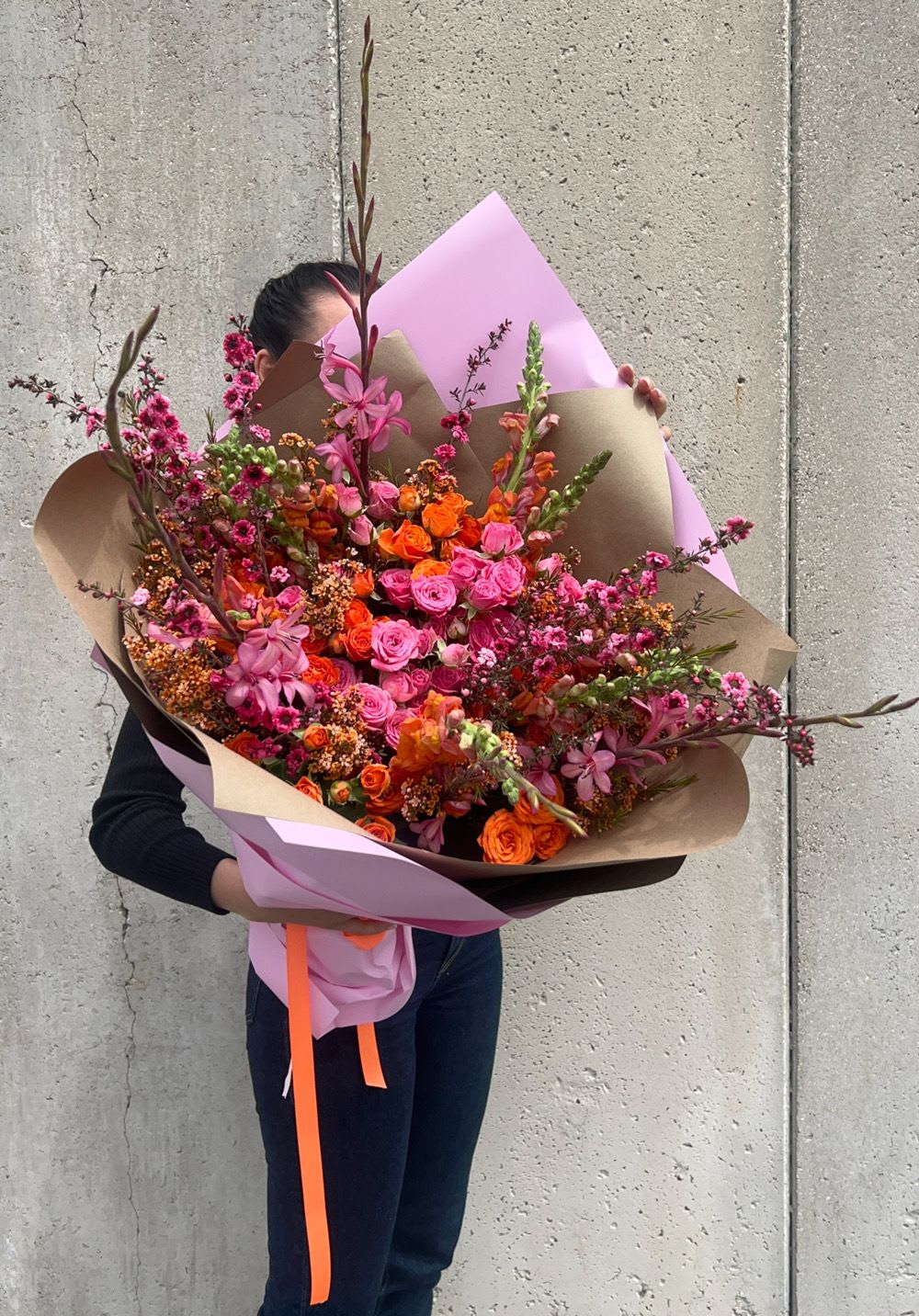 Large bouquet of pink and orange flowers wrapped in paper