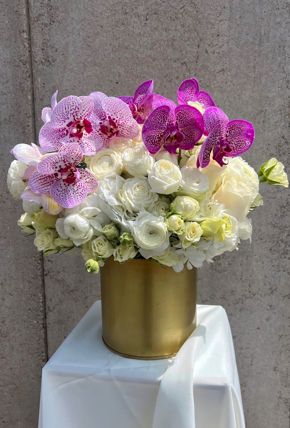 White roses and pink orchids in a gold vase