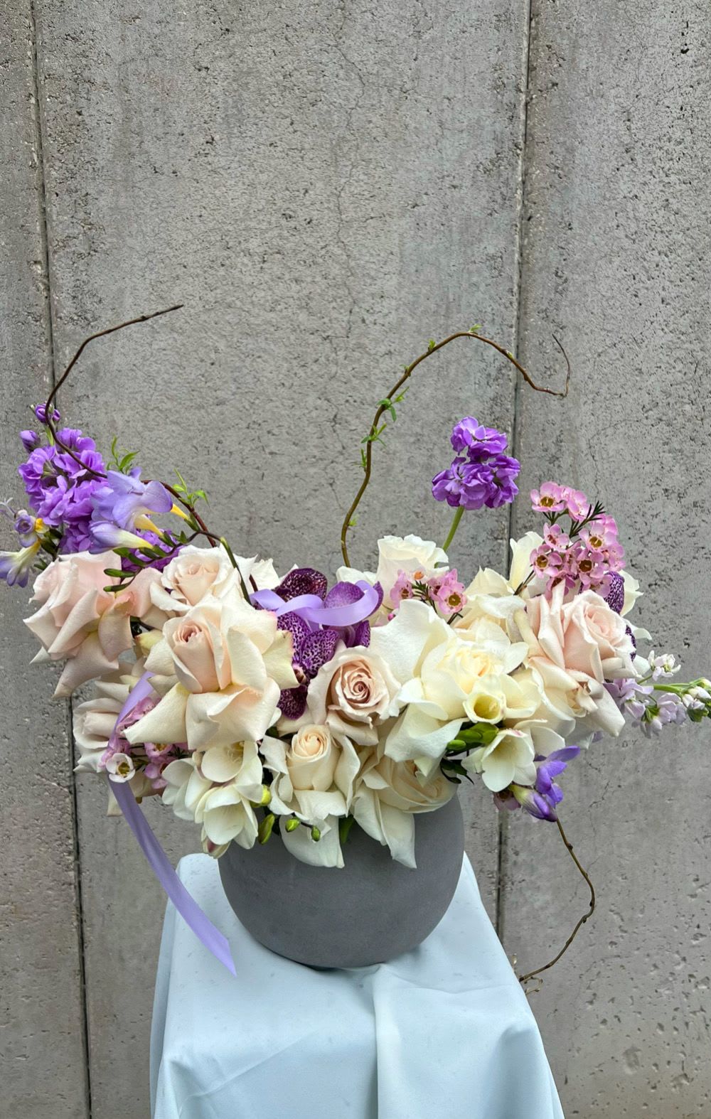 Bouquet of cream and lavender flowers in a gray vase