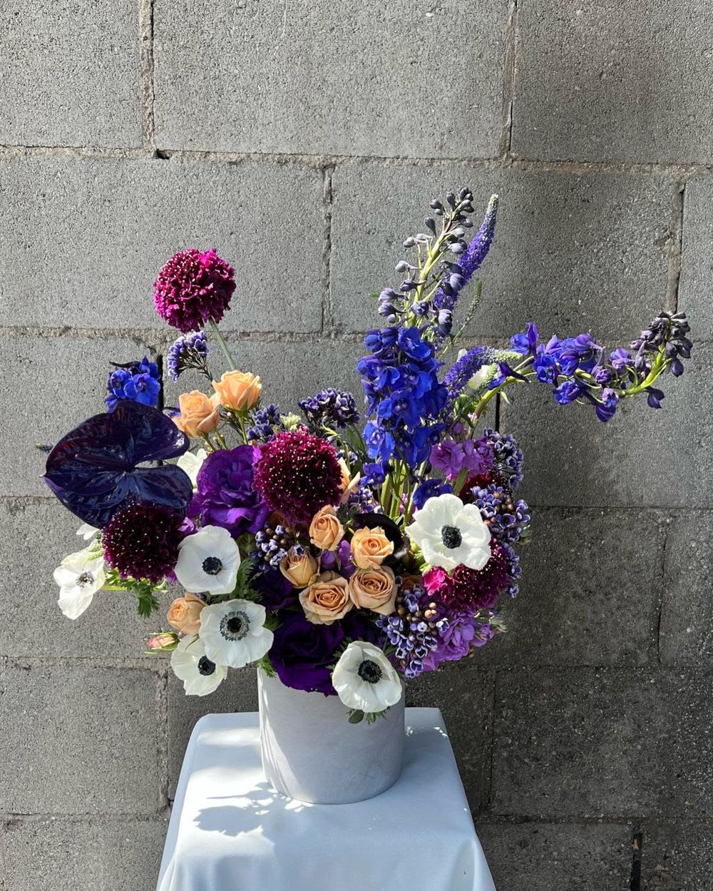 Purple and white floral arrangement in a white vase