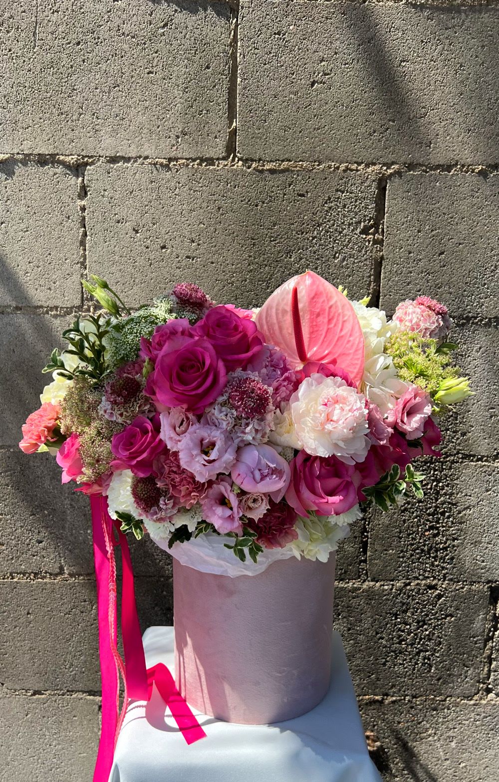 Pink and white bouquet in a pale pink hatbox with a ribbon.