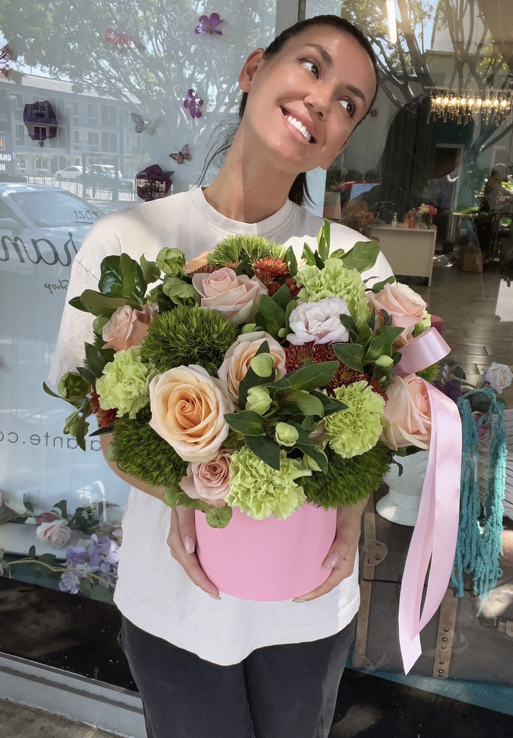 Woman holding a pink box of pastel roses and green carnations