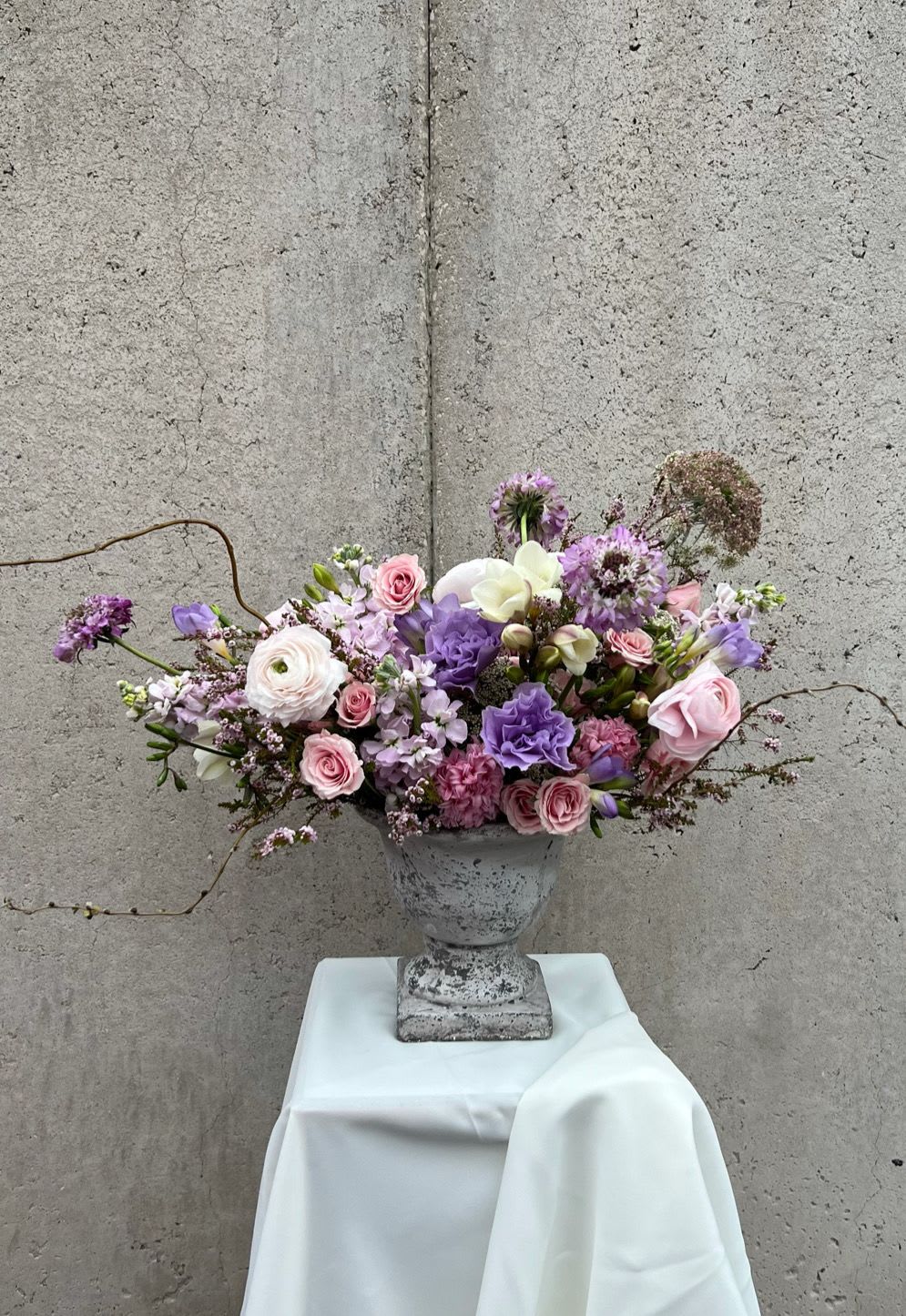 Lavender and pink floral arrangement in a gray urn vase
