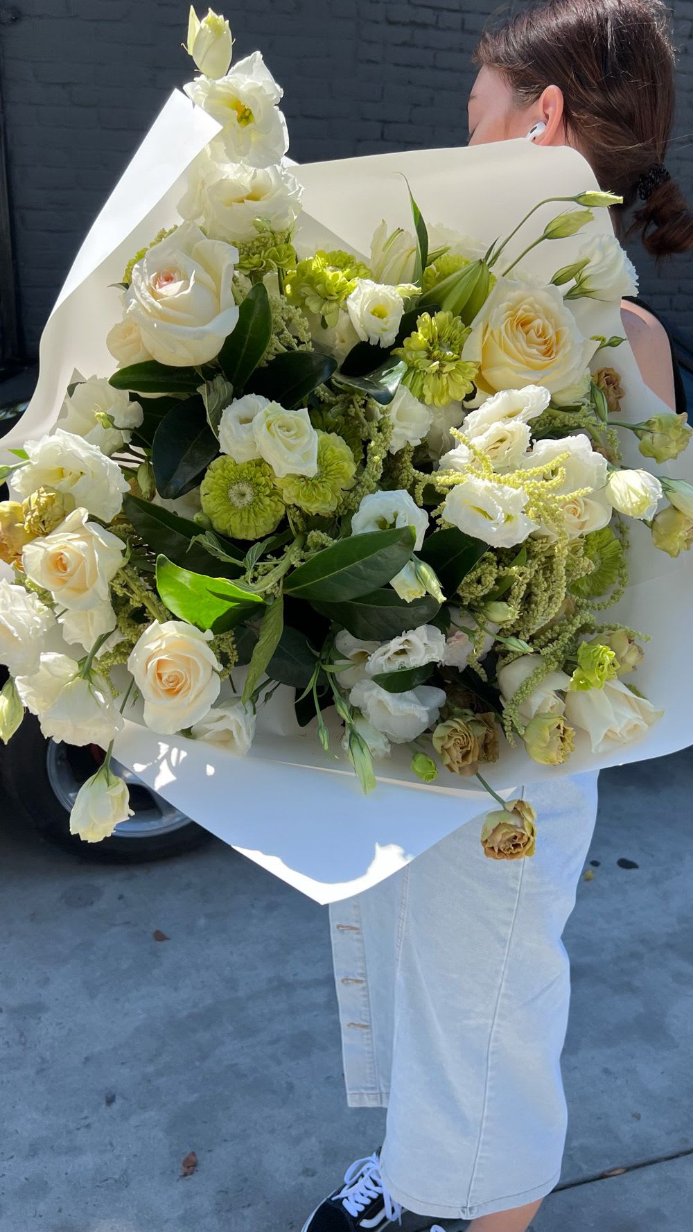 Large bouquet of white and pale green flowers wrapped in white paper
