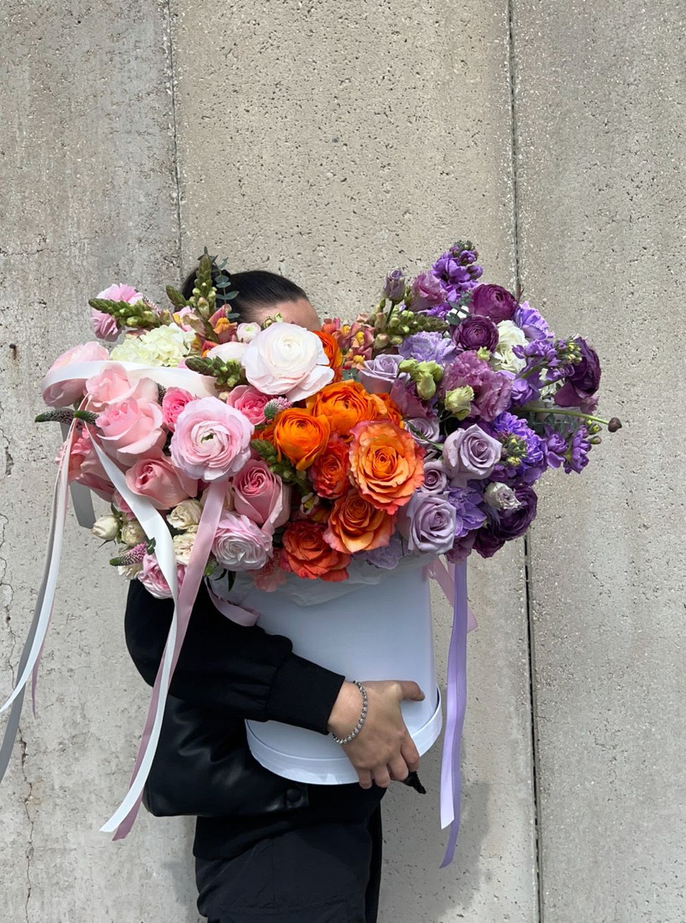 Large bouquet of pink, orange, and purple flowers in a white box