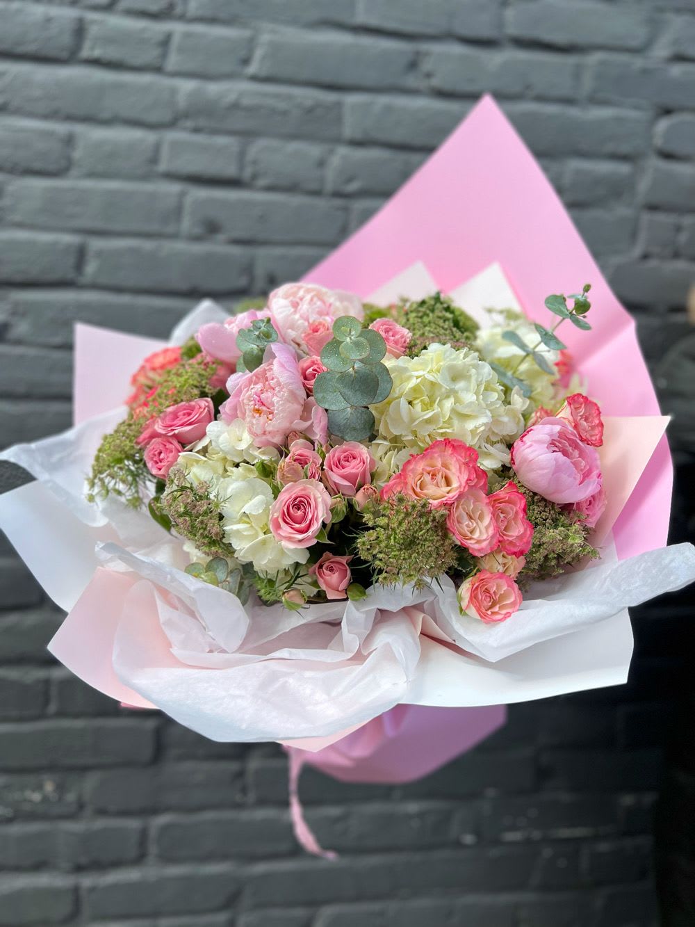 Pink and white bouquet of roses and hydrangeas wrapped in pastel paper