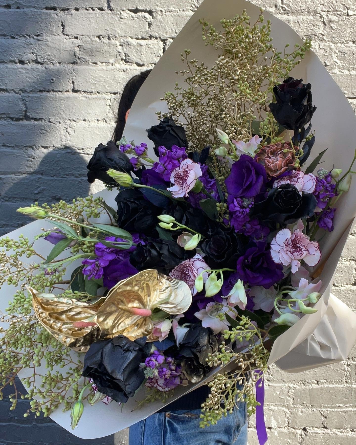 Bouquet of black, purple, and pale pink flowers with gold anthuriums