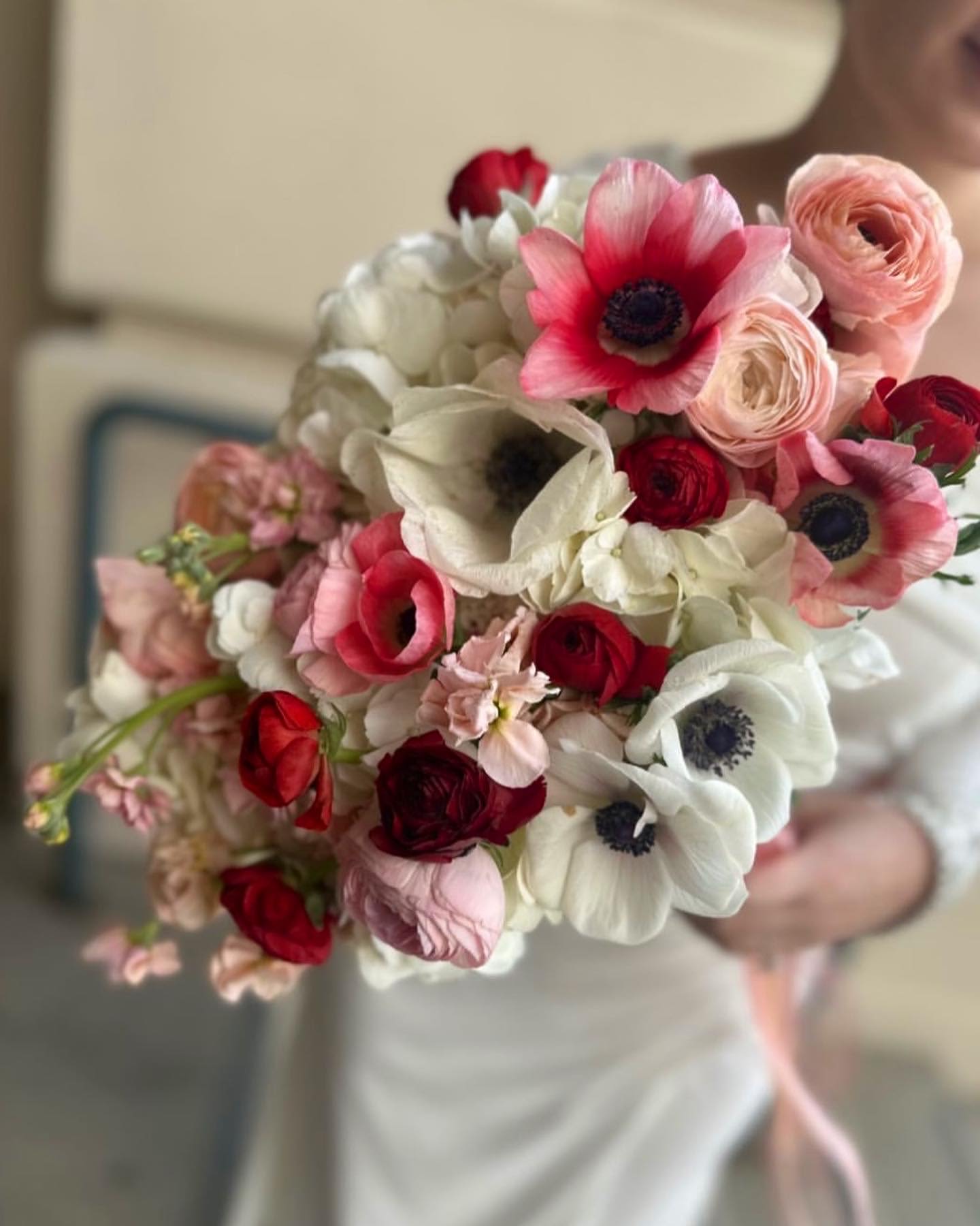 Handheld bouquet of pink, red, and white flowers