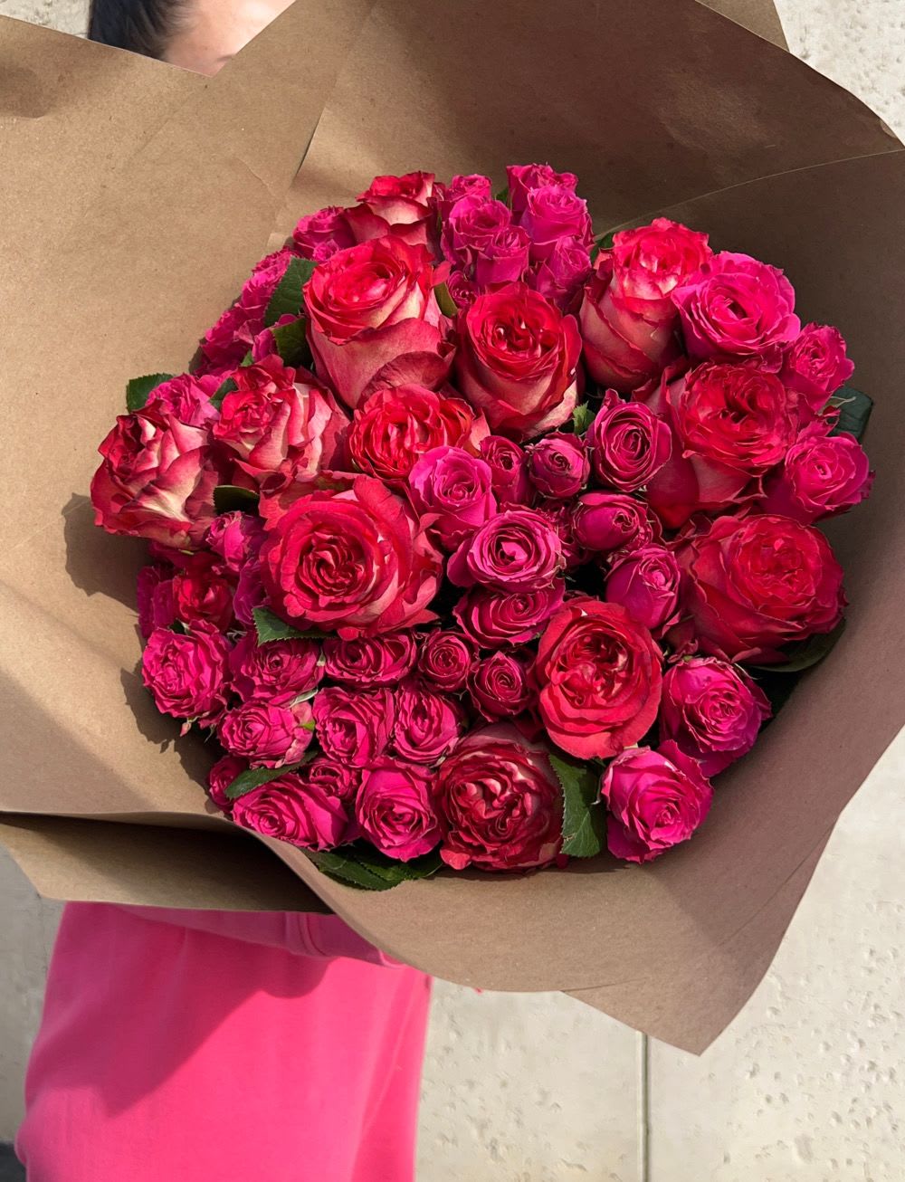 Bouquet of hot pink and red roses wrapped in brown paper