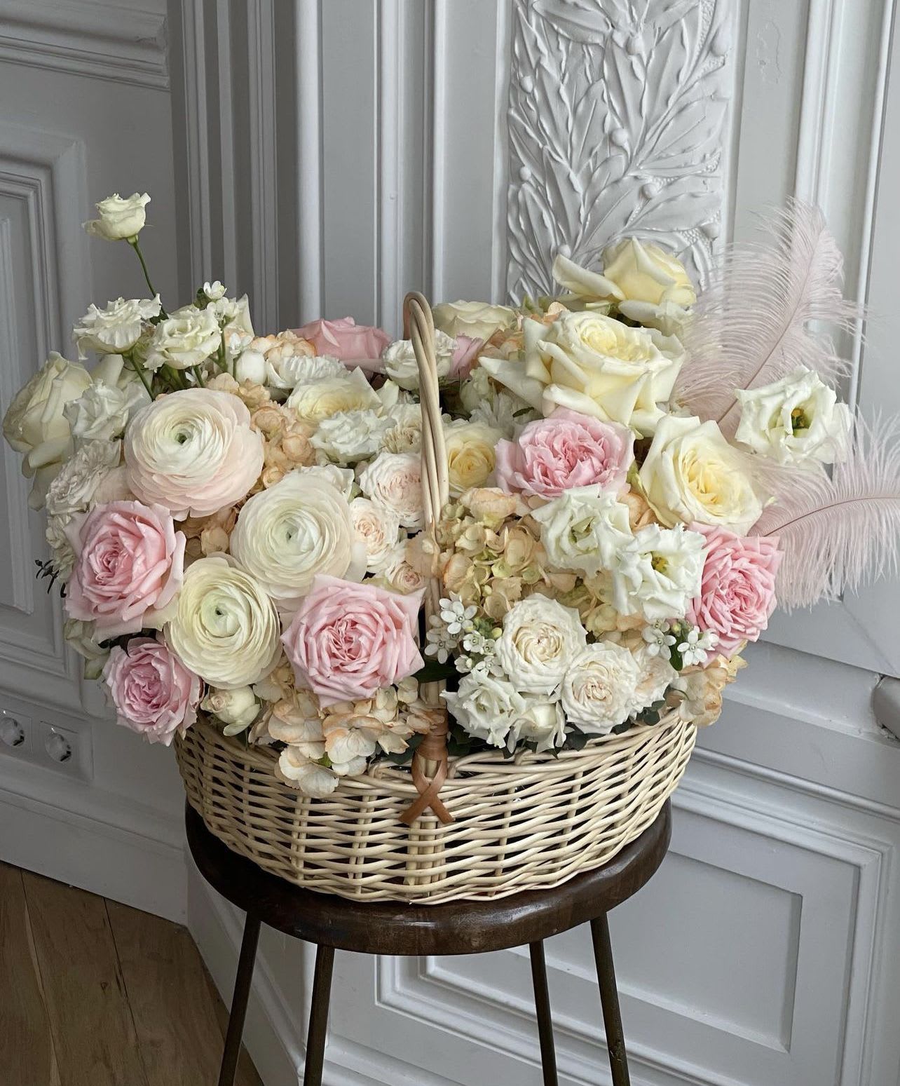 Basket arrangement of pale pink and white roses with feathers