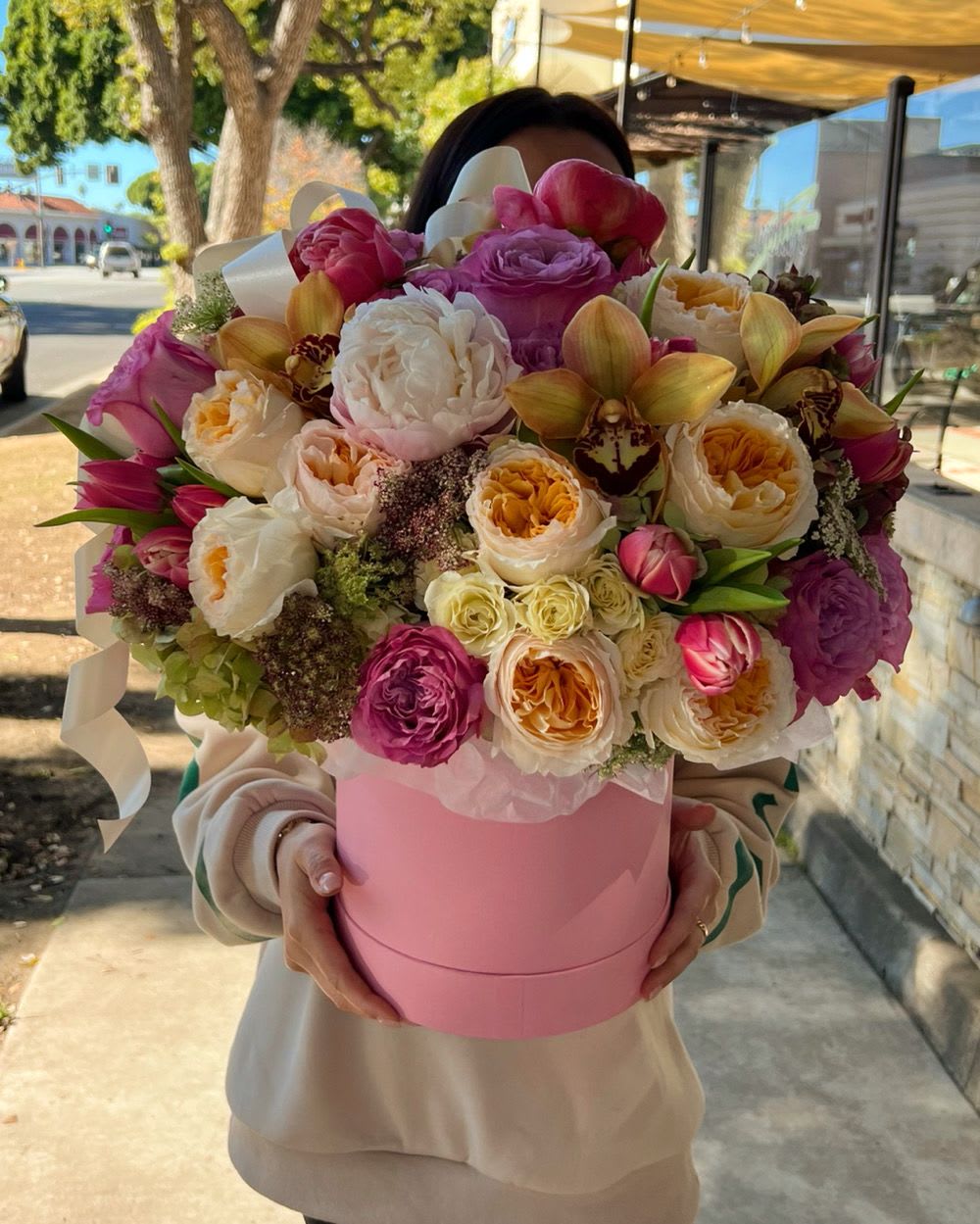 Large bouquet of pink, white, and peach flowers in a pink hat box