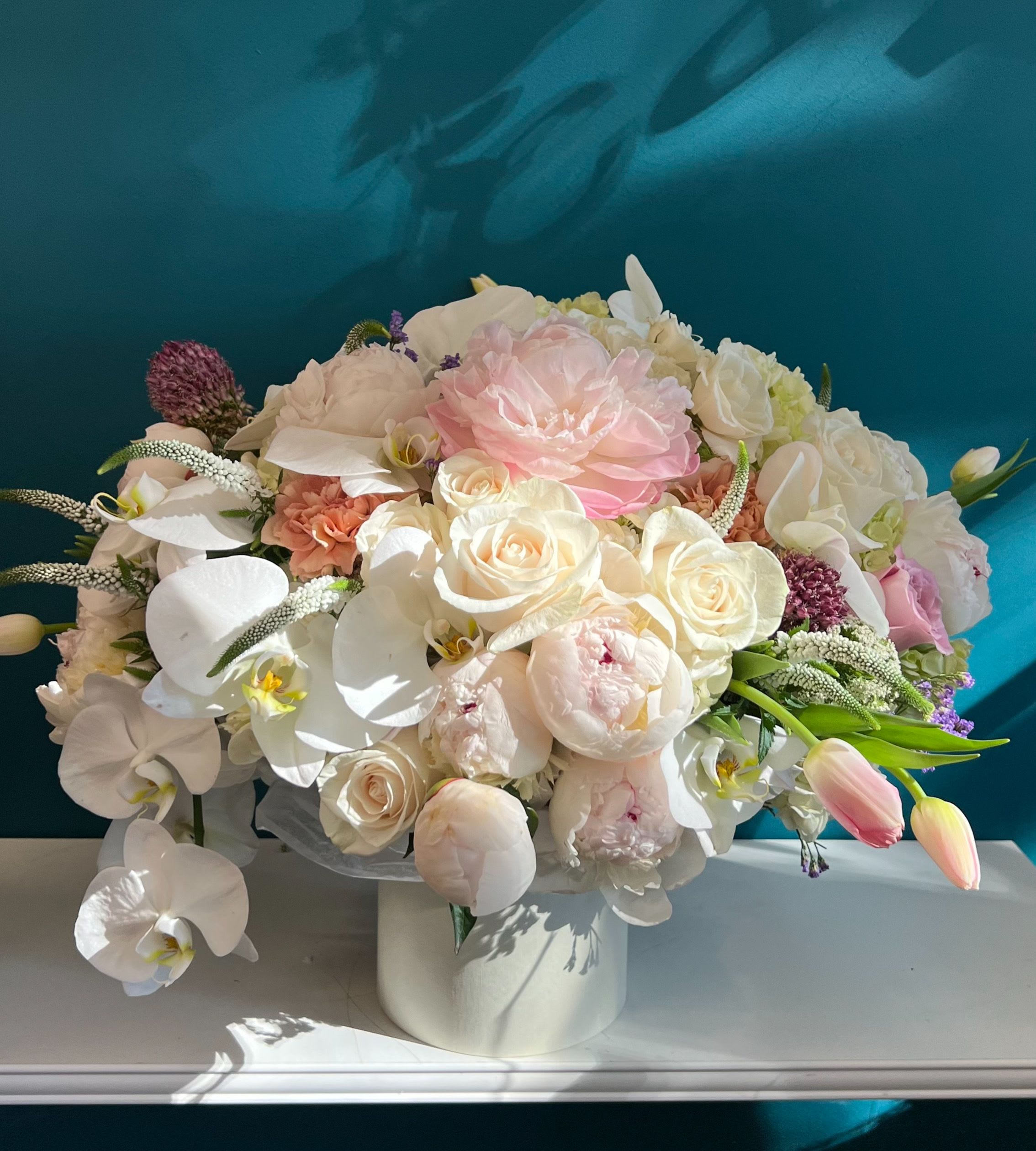 Pastel bouquet of roses, peonies, and orchids in a white vase