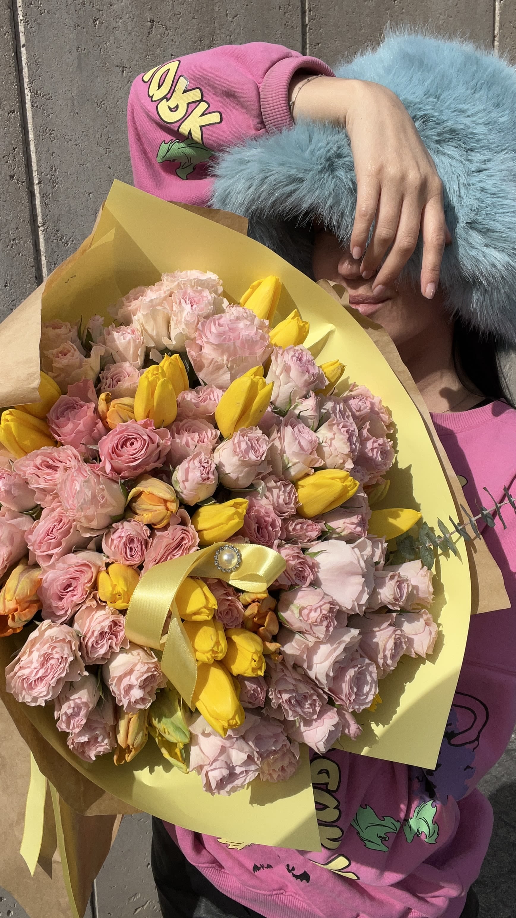 Pink and yellow bouquet wrapped in yellow paper