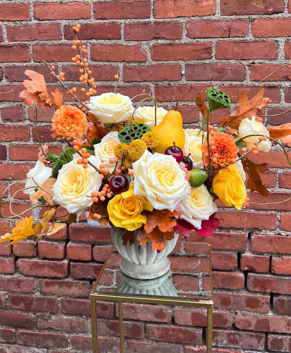 Autumn floral arrangement with roses, dahlias, and berries in a pedestal vase