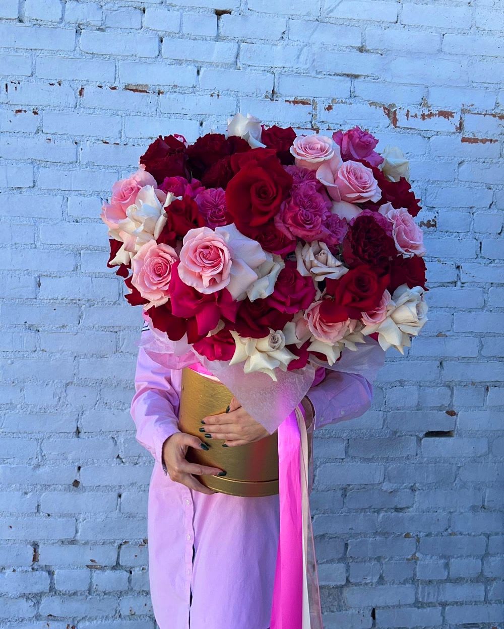 Large bouquet of red, pink, and white roses in a gold box