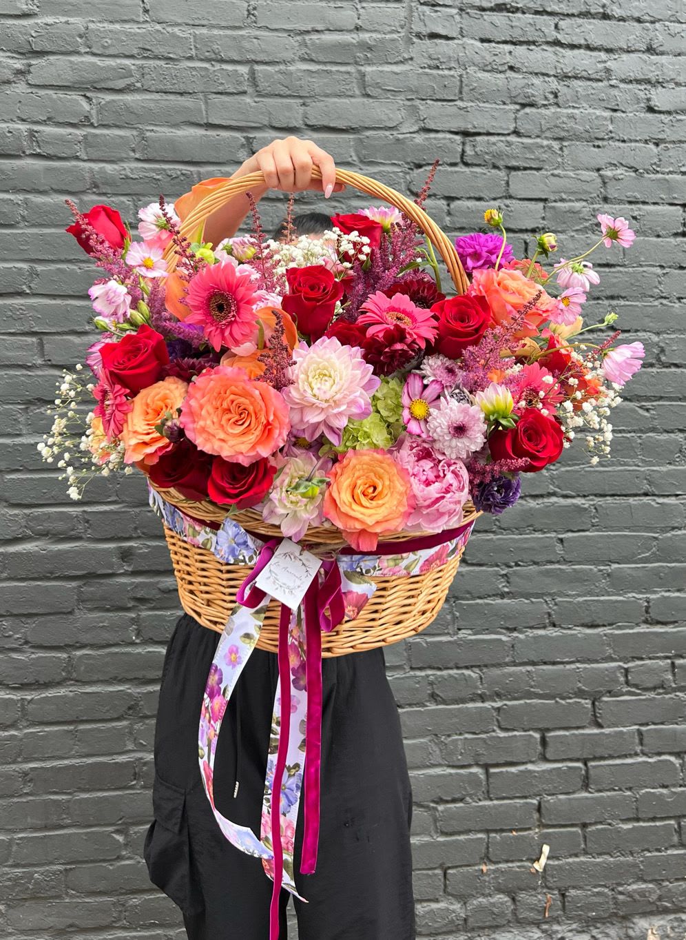 Large wicker basket filled with colorful mixed flowers and ribbon