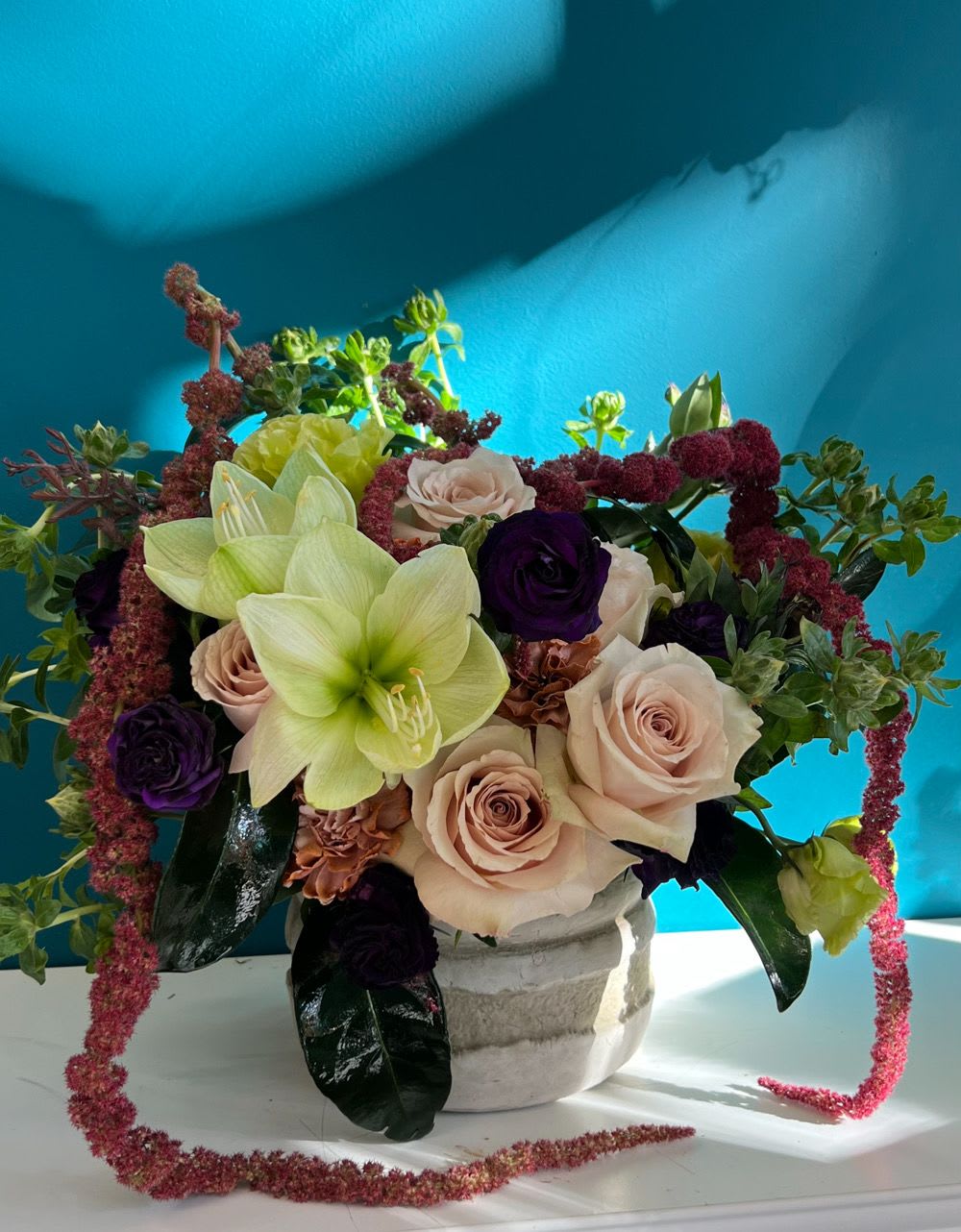 Arrangement of pale roses and green lilies in a white vase