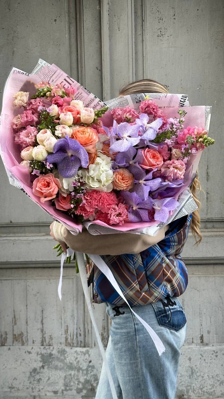 Large bouquet of pink and purple flowers wrapped in paper
