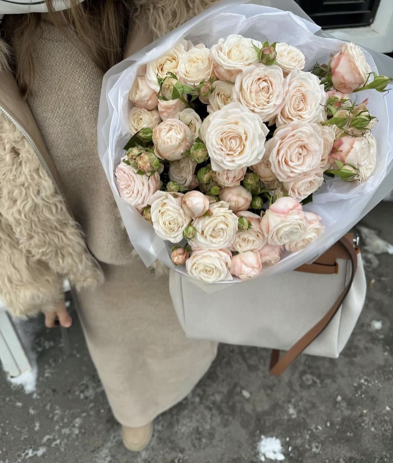 Bouquet of pale pink and white roses wrapped in white paper