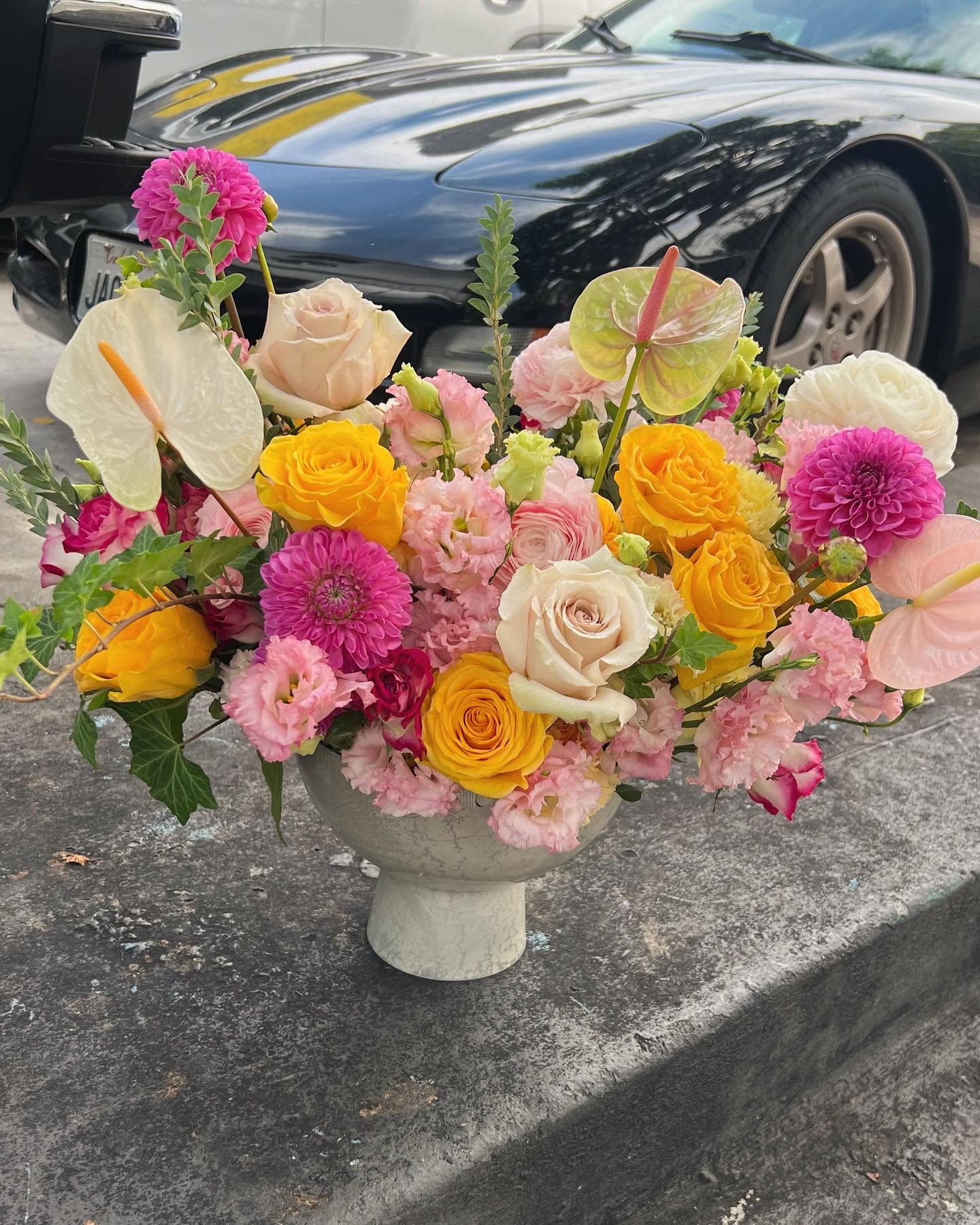 Colorful floral arrangement in a pedestal vase with roses and anthuriums