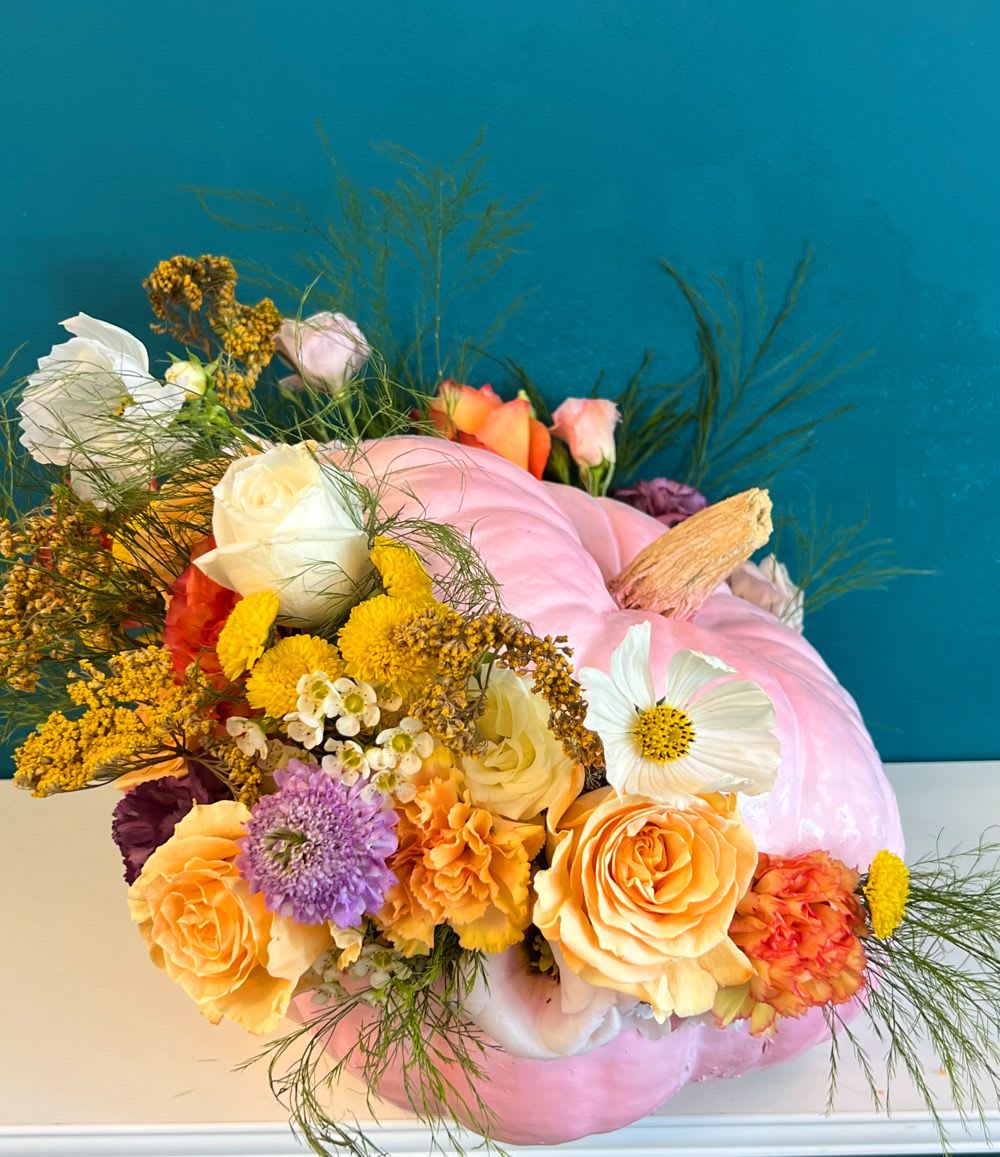Floral arrangement in a pink pumpkin vase with roses and mixed blooms