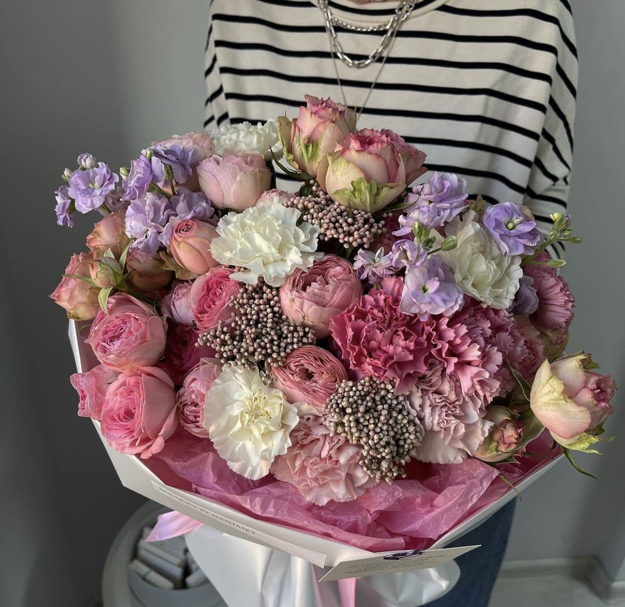 Large bouquet of pink and lavender flowers wrapped in white paper
