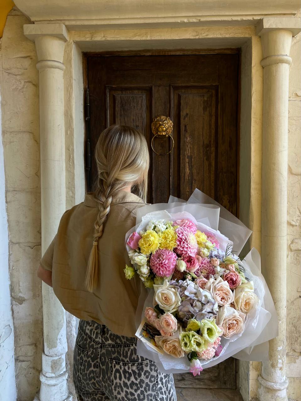 Person holding a large pastel bouquet of mixed flowers