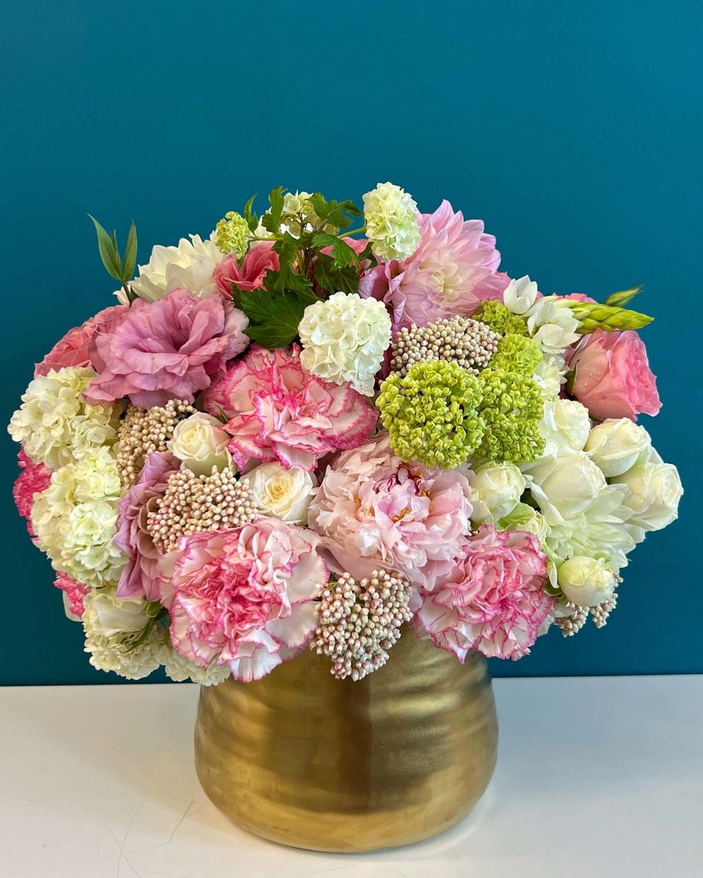Pink and white floral arrangement in a gold vase