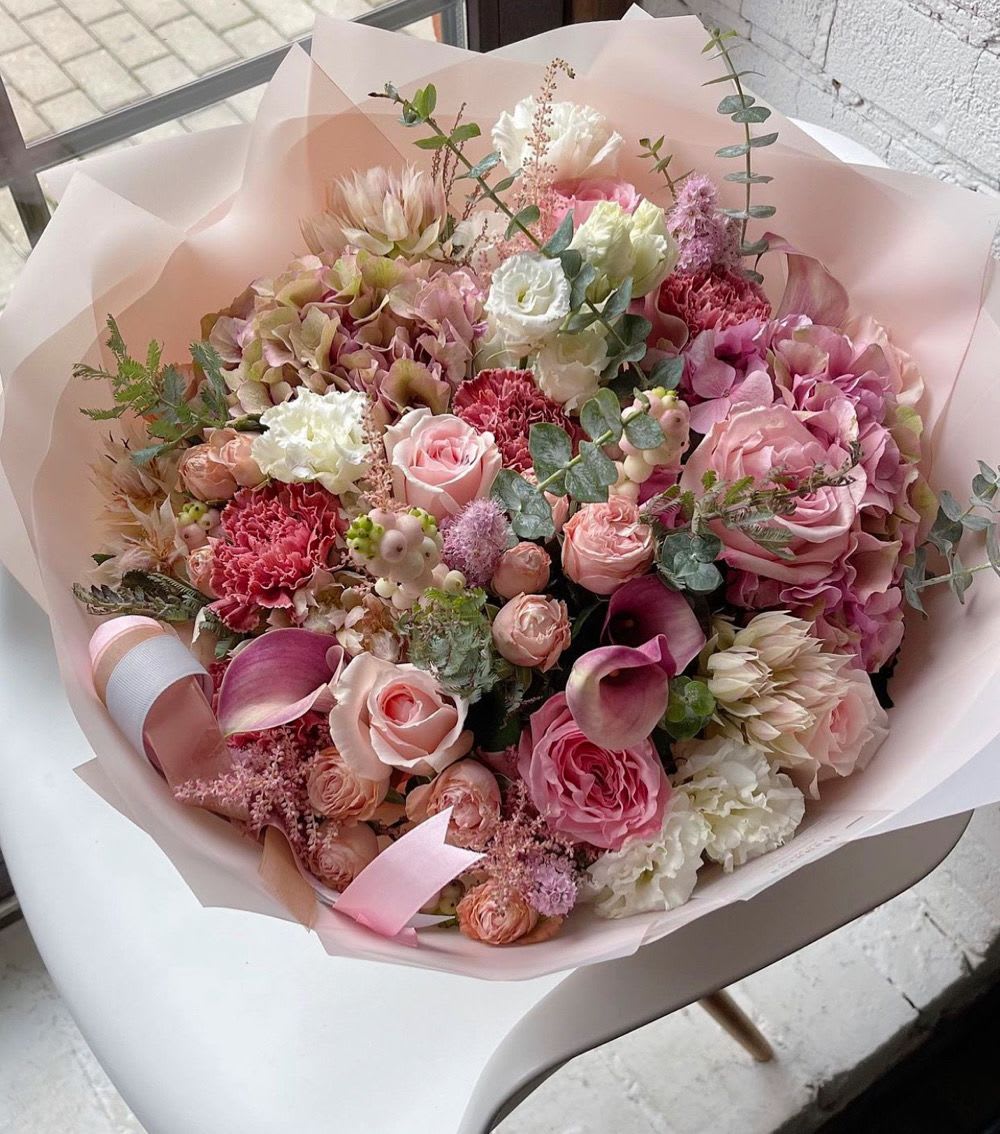 Pink mixed bouquet with roses, hydrangeas, and calla lilies wrapped in pale paper