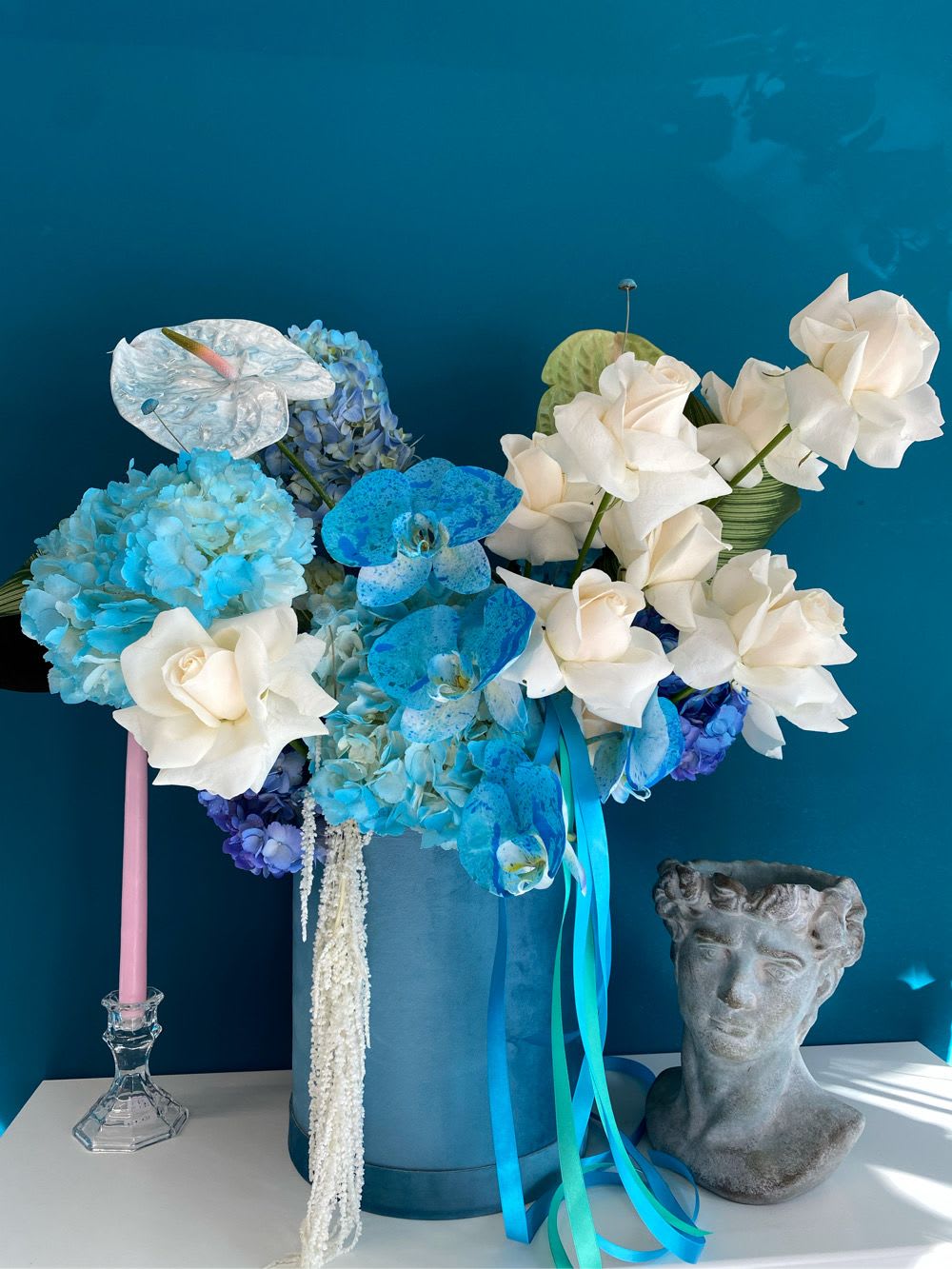 Blue and white floral arrangement in a tall blue box with ribbons