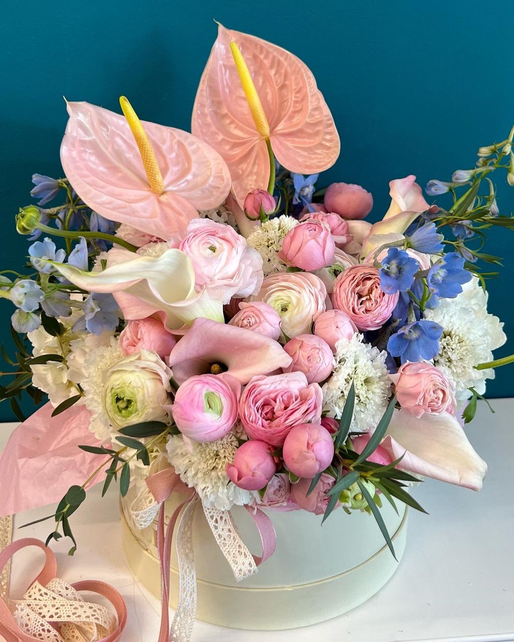 Pink and white bouquet with anthuriums, roses, and calla lilies in a round box