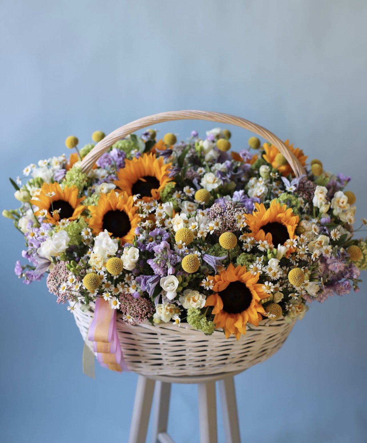 Basket of sunflowers and mixed pastel flowers with a ribbon