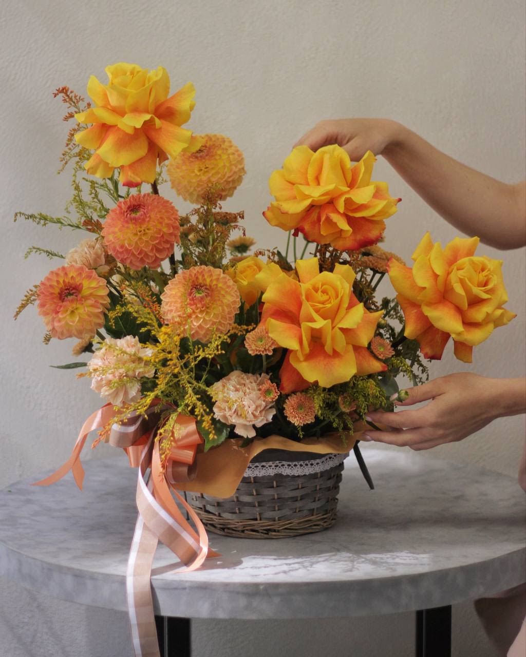 Basket arrangement of yellow-orange roses and peach pompon flowers