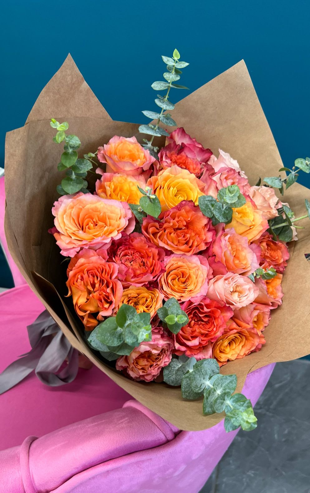 Bouquet of orange and pink roses wrapped in brown paper