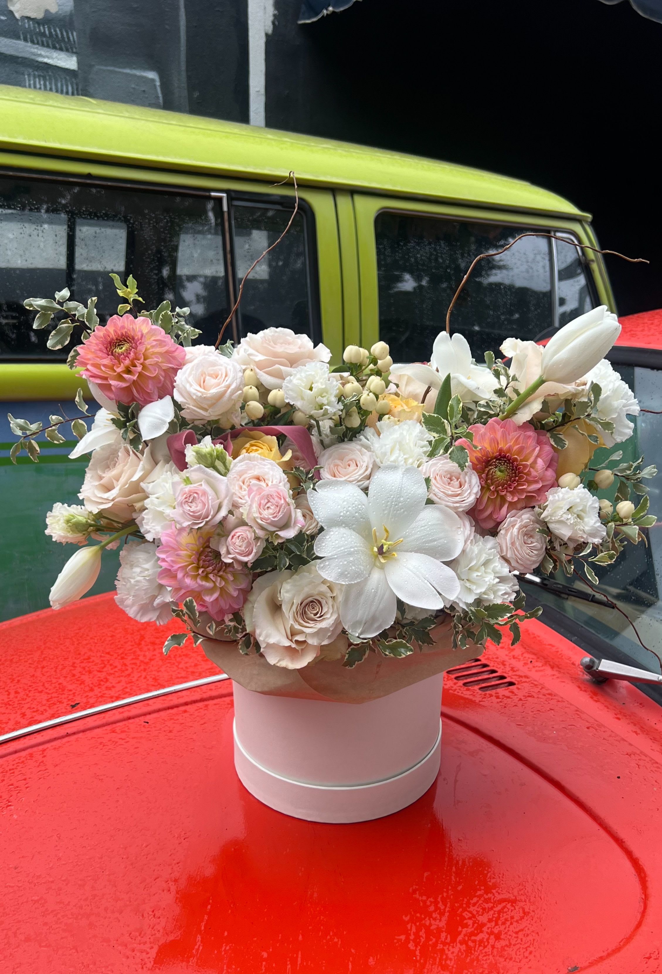 Pink and white floral arrangement in a round hatbox