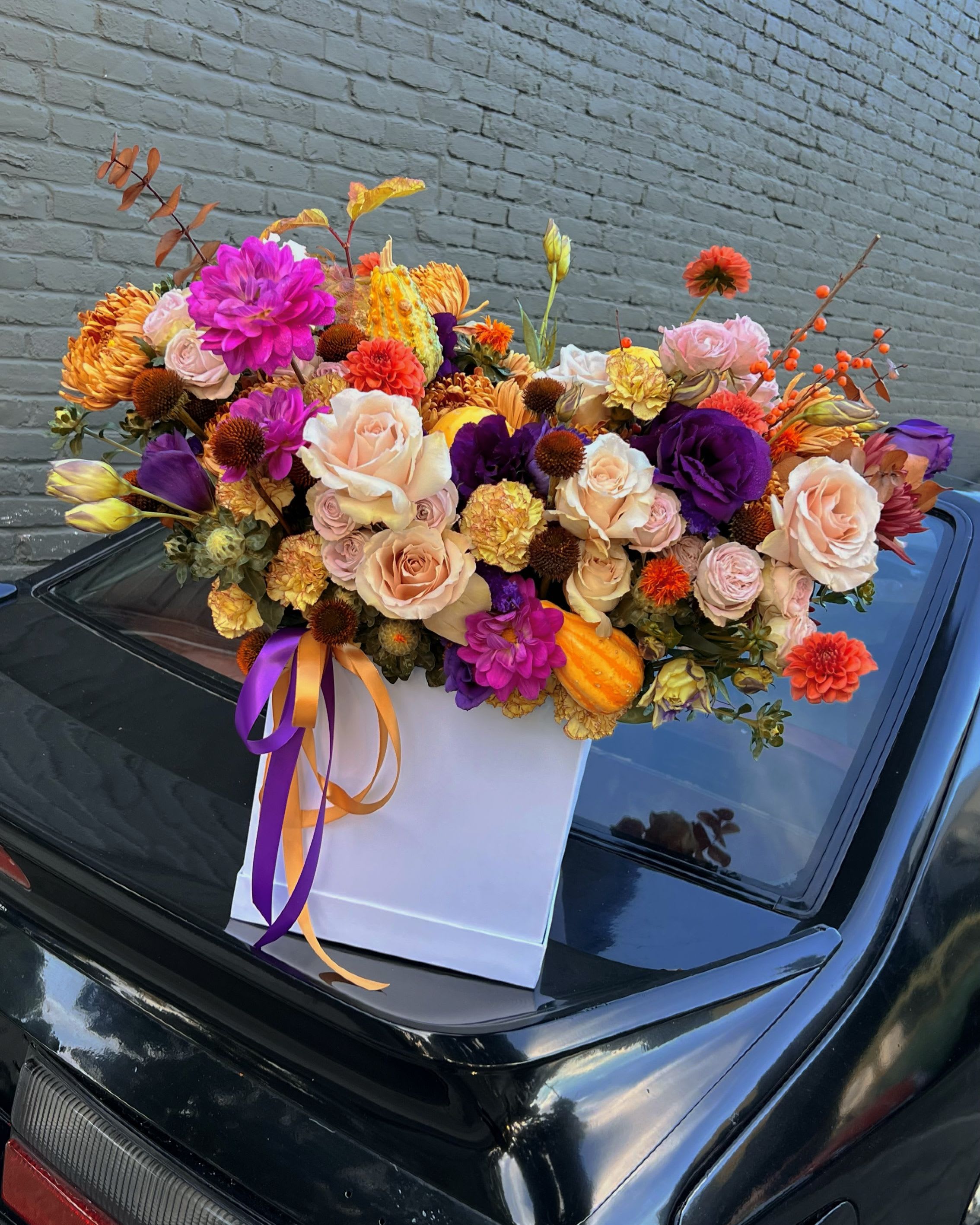 Mixed bouquet in a white gift box with purple and orange ribbons
