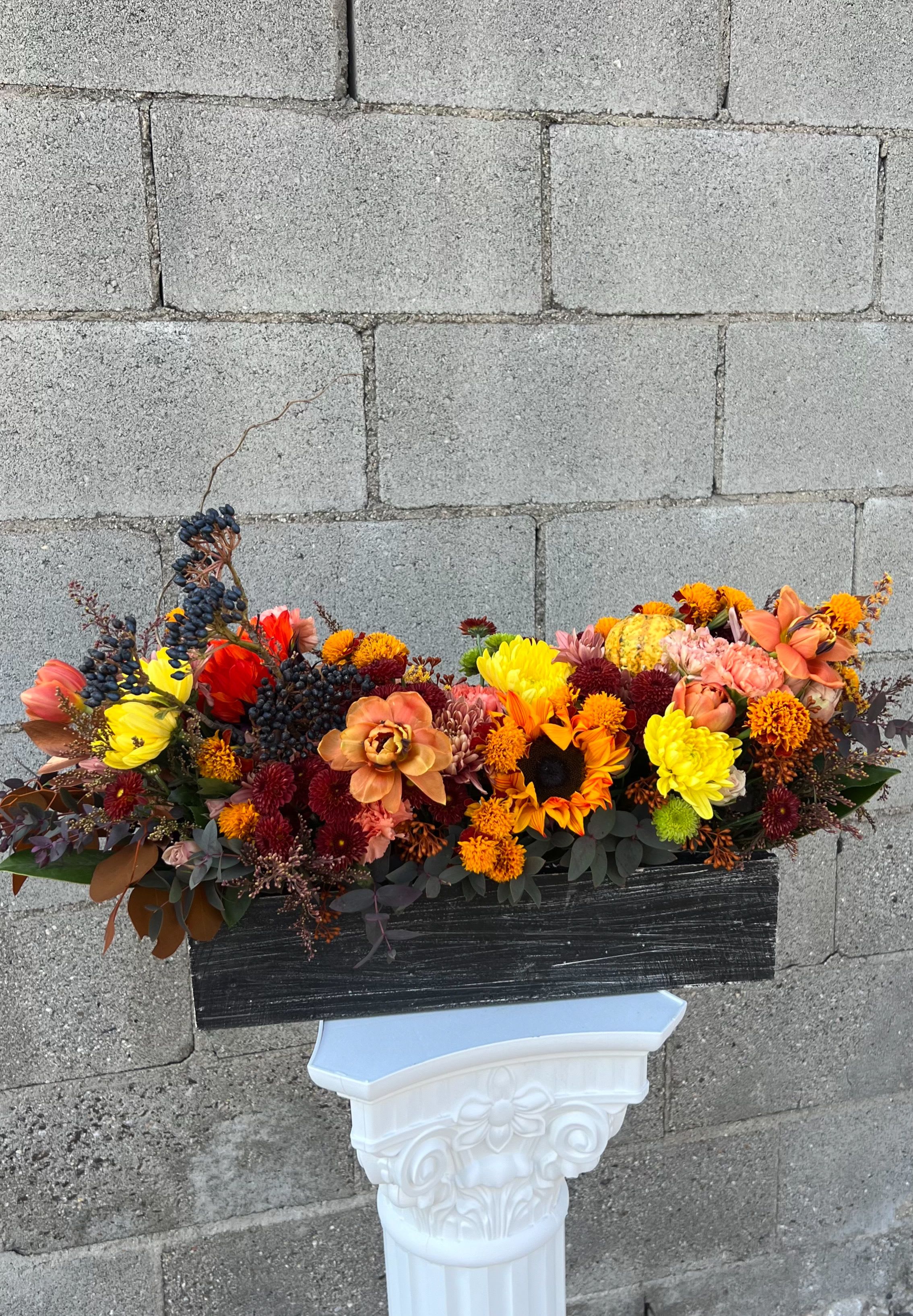 Autumn floral arrangement with sunflowers, mums, and berries in a black container