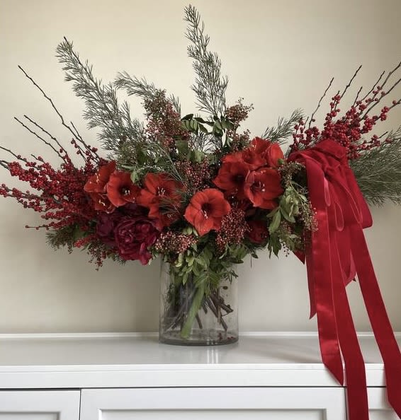 Red floral arrangement in a clear glass vase with a large red ribbon