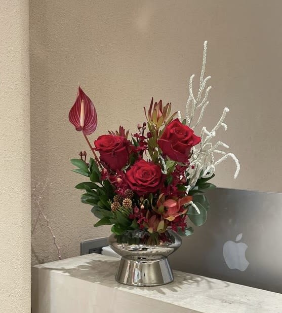 Red rose arrangement in a silver vase with white decorative branches