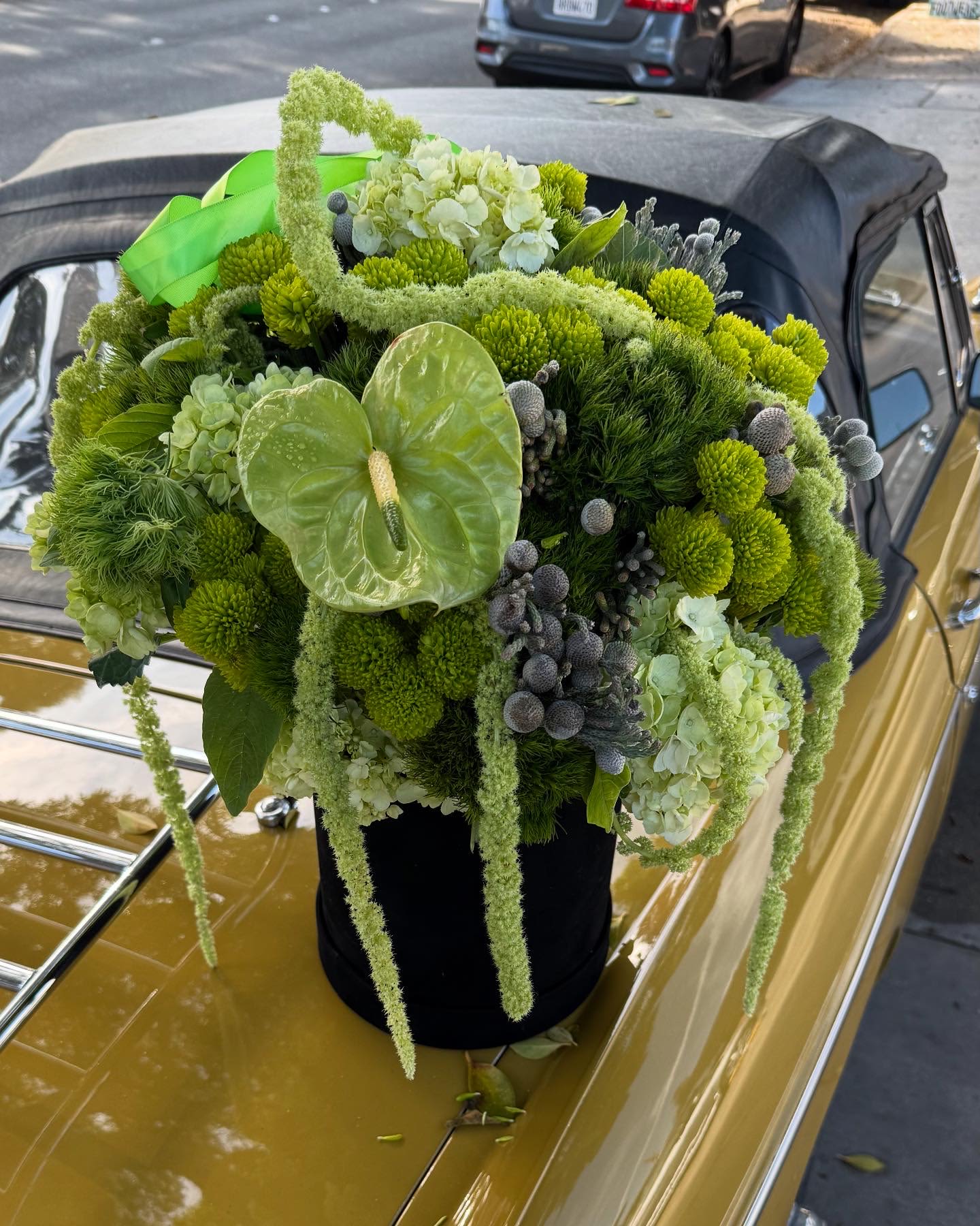 Green floral arrangement with hydrangeas and anthurium on a car